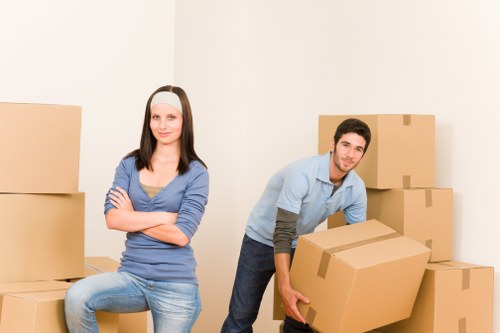 Movers carrying furniture through a narrow staircase in a Haringey flat